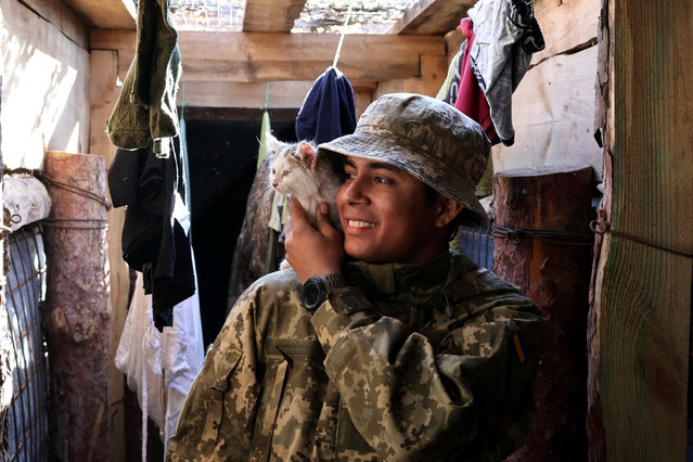 In this handout photograph taken on November 15, 2025 and released on November 16, 2025 by the press service of the 65th Mechanized Brigade of Ukrainian Armed Forces, a Colombian volunteer soldier pets a cat at an undisclosed location in Zaporizhzhia region, amid the Russian invasion of Ukraine. (Photo by Andriy Andriyenko/65th Mechanized Brigade of Ukrainian Armed Forces/AFP Photo)