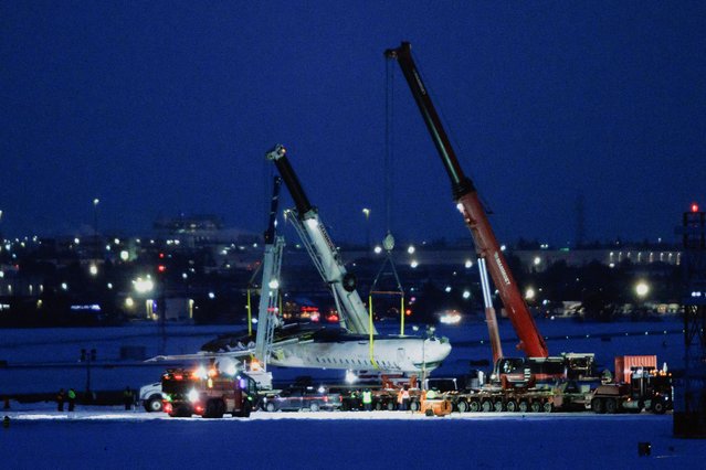 The wreckage of a Delta Air Lines operated CRJ900 aircraft is hoisted onto a truck on the runway as cleanup begins after a plane crash at Toronto Pearson International Airport in Mississauga, Ontario, Canada, on February 19, 2025. (Photo by Cole Burston/Reuters)