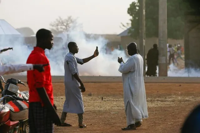 A man uses a phone as a riot broke out after the arrival of the rescued JSS Jangebe schoolgirls in Jangebe, Zamfara, Nigeria on March 3, 2021. Police fired tear gas and soldiers shot their guns into the air in northwest Nigeria as violence broke out amid the return of 279 kidnapped schoolgirls to their families on Wednesday, a day after their release. (Photo by Afolabi Sotunde/Reuters)
