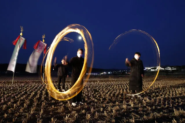 People twirl cans with holes filled with burning wood chips and straw to celebrate the first full moon of the Lunar New Year, in Siheung, South Korea, Friday, February 26, 2021. (Photo by Lee Jin-man/AP Photo)