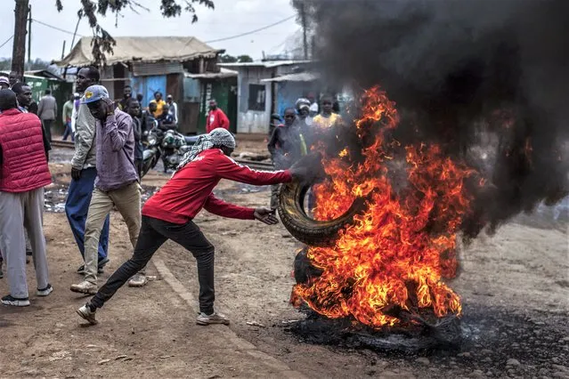 A protester burns tyres to block the road in the Kibera neighborhood of Nairobi, Kenya, Wednesday, July 12, 2023. (Photo by Samson Otieno/AP Photo)