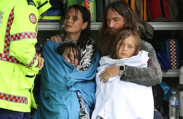 A family receives medical attention after the Marine Rescue boat that rescued them from rising floodwaters capsized in strong currents, as the state of New South Wales experiences widespread flooding and severe weather, in the suburb of Sackville North in Sydney, Australia, March 23, 2021. (Photo by Loren Elliott/Reuters)