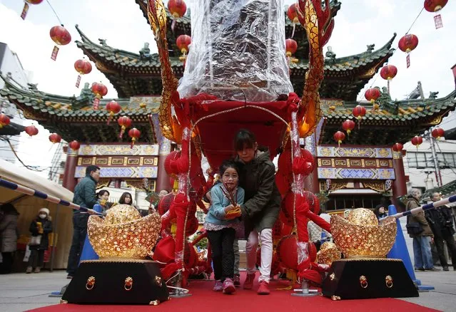 A girl and her mother walk through a Chinese portable shrine during the Chinese Lunar New Year at Chinatown in Yokohama, south of Tokyo February 19, 2015. (Photo by Yuya Shino/Reuters)