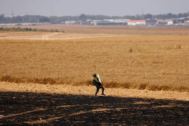 An Israeli soldier carries an artillery shell in a field next to his artillery unit near the border between Israel and the Gaza Strip, on its Israeli side on May 14, 2021. (Photo by Amir Cohen/Reuters)