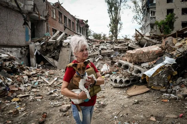 Lubov Jarova holds her dog, Peremoha (victory), as she walks among the rubble of a school in the frontline town of Orikhiv, Zaporizhzhia Oblast, Ukraine, 07 September 2023, amid the Russian invasion. The school was operating as a center for distribution of humanitarian aid until the premises were hit by two consecutive air strikes. Lubov says that her dog saved her life. Following the first strike, she ran after it outside the school when the second strike happened, destroying the building and killing seven people. Today Lubov lives in Zaporizhzhia, around 65 kilometers north-west, and she occasionally brings humanitarian aid to her hometown of Orikhiv, located less than 10 kilometers from the nearest Russian army position. Before the war, Orikhiv had a population of over 14,000. The town is currently home to around 700 people, witnessing daily attacks from Russian forces. (Photo by Kateryna Klochko/EPA/EFE)