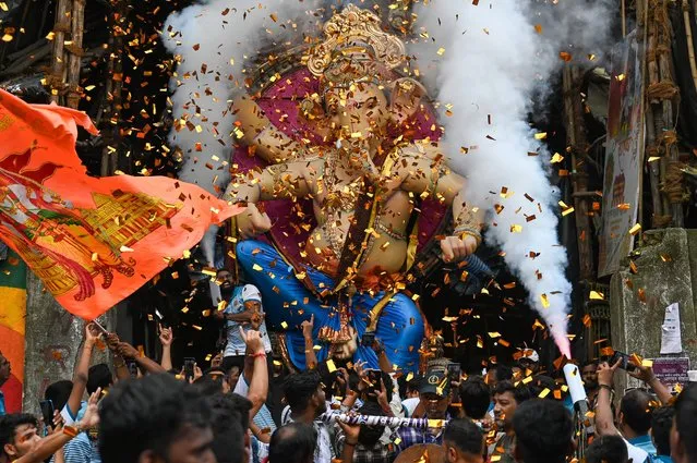 Devotees carry an idol of the elephant-headed Hindu deity 'Ganesha' during a procession along a street in Mumbai on September 17, 2023, ahead of the Ganesh Chaturthi festival. (Photo by Punit Paranjpe/AFP Photo)