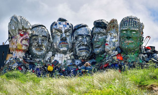 A woman photographs an artwork “Mount Recyclemore”, an artwork depicting the G7 leaders looking towards Carbis Bay, made from electronic waste by artists Joe Rush and Alex Wreckage, ahead of the G7 summit, at Hayle Towans in Cornwall, Britain, June 8, 2021. (Photo by Ben Birchall/PA Images via Getty Images)