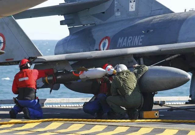 A pilot (R) and crew check ordnance under a Super Etendard fighter jet aboard France's Charles de Gaulle aircraft carrier which continues its mission in the Gulf, January 28, 2016. (Photo by Philippe Wojazer/Reuters)
