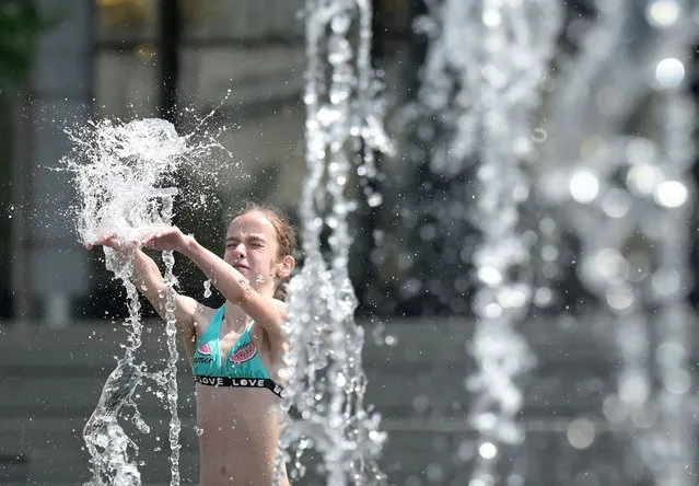 A girl cools off in a fountain on June 15, 2021 in downtown Moscow, as temperatures have reached 27 degrees Celsius. (Photo by Natalia Kolesnikova/AFP Photo)