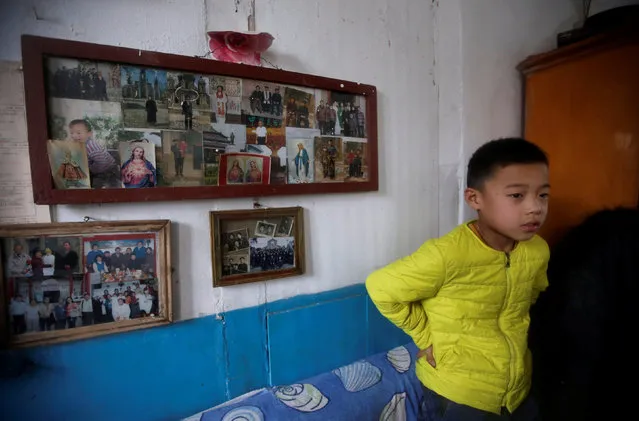 Wu Jia stands near a photo frame with pictures of his family before he goes to attend a Christmas mass at a Catholic church on the outskirts of Taiyuan, North China's Shanxi province, December 24, 2016. (Photo by Jason Lee/Reuters)