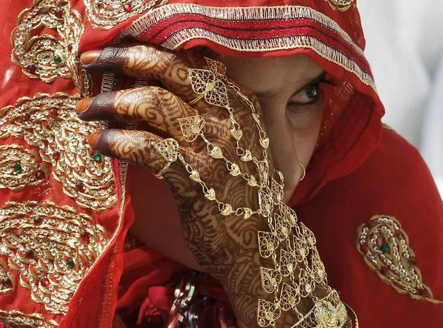 A Muslim bride waits for the start of a mass marriage ceremony in the western Indian city of Ahmedabad March 21, 2015. A total of 112 Muslim couples from various parts of Ahmedabad on Saturday took wedding vows during the mass marriage ceremony organised by a Muslim voluntary organisation, organisers said. (Photo by Amit Dave/Reuters)
