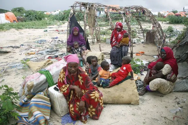 Somali displaced people sit after heavy floods hit their makeshift shelter, in Mogadishu, Somalia, Monday, November 13, 2023. Somali authorities say floods caused by torrential rainfall have killed at least 30 people in various parts of the country. (Photo by Farah Abdi Warsameh/AP Photo)