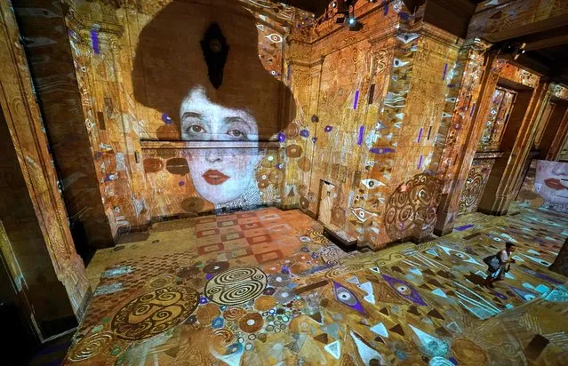 A person attends the opening press preview of Hall des Lumières, New York City’s new permanent center for immersive digital art experiences, on September 13, 2022. The immersive exhibit at the former Emigrant Savings Bank features the iconic works of Gustav Klimt and several other artists. (Photo by Timothy A. Clary/AFP Photo)