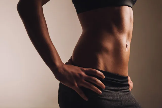 Close-up shot of young woman waist with muscular abdominal muscles. Abs of fit female athlete. (Photo by Alamy Stock Photo)