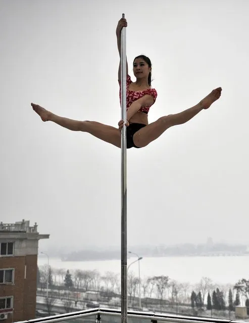 This picture taken on December 17, 2013 shows a pole dancer practising after it snowed in Tianjin during a promotional event by members of China's national pole dancing team and students of the sport. (Photo by AFP Photo)