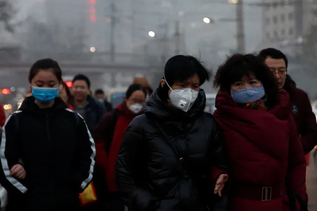 People wear face masks as they cross a street on a polluted day in Beijing, China January 4, 2017. (Photo by Thomas Peter/Reuters)