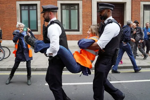 Police officers detain a Just Stop Oil demonstrator who had glued themselves to the ground during a protest, in London, Britain on October 5, 2022. (Photo by Maja Smiejkowska/Reuters)