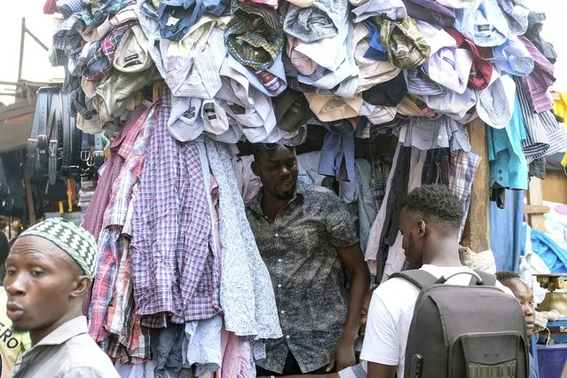 A seller of second hand clothes interacts with a customer at Owino Market in Kampala, Uganda, Friday, September 15, 2023. Downtown Kampala’s Owino Market has long been a go-to enclave for rich and poor people alike looking for affordable but quality-made used clothes, underscoring perceptions that Western fashion is superior to what is made at home. But, despite their popularity, secondhand clothes are facing increasing pushback. (Photo by Hajarah Nalwadda/AP Photo)