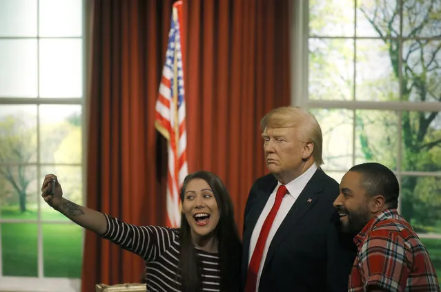 Madame Tussauds' employees take a selfie with the wax figure of US President-elect Donald Trump, as they unveil the figure just days ahead of the American's Presidential Inauguration in Washington in London, Wednesday, January 18, 2017. The figure will now reside in Madame Tussauds' London Oval Office alongside fellow famous politicians and global icons also immortalised in wax. (Photo by Frank Augstein/AP Photo)