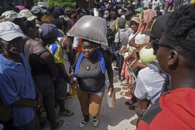 A woman carries food aid in Camp Perrin, Haiti, Friday, August 20, 2021, six days after a 7.2 magnitude earthquake hit the area. (Photo by Fernando Llano/AP Photo)