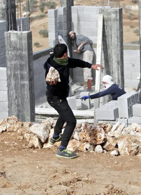 Palestinians throw stones at Israeli settlers who are later detained by Palestinian villagers in a building under construction near the West Bank village of Qusra, southeast of the city of Nablus, Tuesday, January 7, 2014. (Photo by Nasser Ishtayeh/AP Photo)
