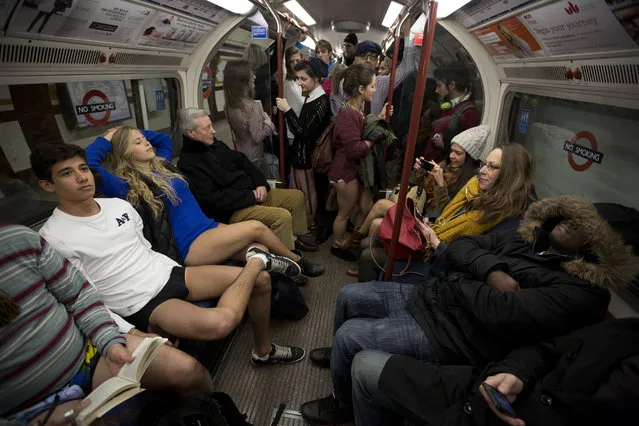 People take part in the “No Trousers Tube Ride” event next to other passengers on an underground train in London, Sunday, January 12, 2014. The stunt was held to coincide with the “Global No Pants Subway Ride”, where passengers board subway cars in the middle of winter without wearing trousers and act normally. (Photo by Matt Dunham/AP Photo)