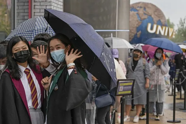 Women wearing face masks to help protect themselves from coronavirus wave as they line-up to enter a merchandise store at the Universal Studios Beijing in Beijing, Monday, September 20, 2021. Thousands of people brave the rain visit to the newest location of the global brand of theme parks which officially opens on Monday. (Photo by Andy Wong/AP Photo)