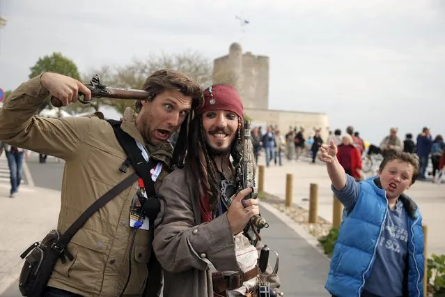 Julien Godard, dressed as Captain Sparrow, right, poses for souvenir picture prior to the departure of the replica of the frigate Hermione, used to bring French troops and funds to American revolutionaries in 1780, in Fouras, southwest France, on his way for its transatlantic voyage, Saturday, April 18, 2015. (Photo by Francois Mori/AP Photo)