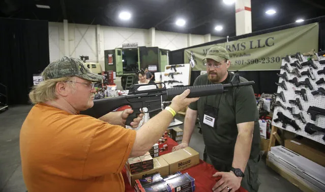 Beryl Paffrath, left, handles a Akdal 1919, AR-15 style, 12 gauge shotgun, while Matthew T. Kitterman, of MTK Arms, looks on during the PrepperCon expo Friday, April 24, 2015, in Sandy, Utah. (Photo by Rick Bowmer/AP Photo)