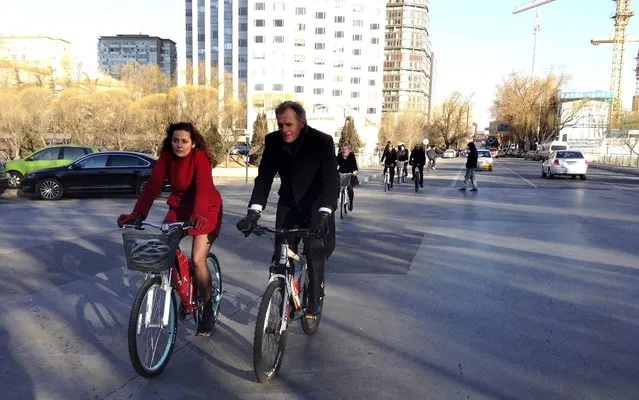 Pia Olsen Dyhr (L), Danish Minister for Transport, rides a bicycle with Danish Ambassador to China Friis Arne Petersen as they promote green transportation on a street in Beijing, January 20, 2014. (Photo by Reuters/China Daily)