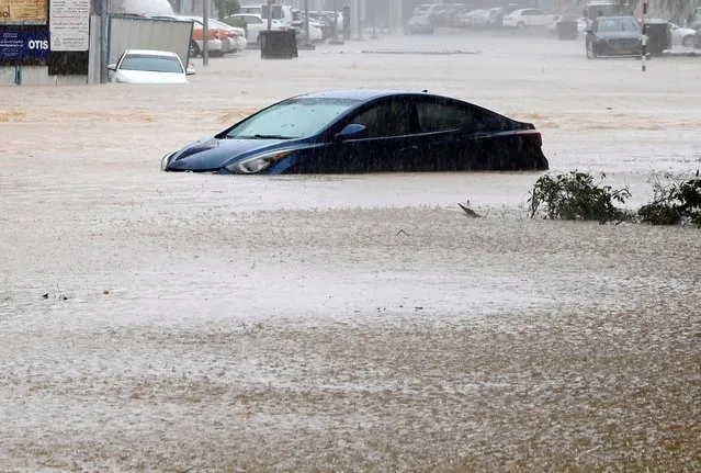 A car is partially submerged on a flooded street as Cyclone Shaheen makes landfall in Muscat Oman, October 3, 2021. (Photo by Sultan Al Hassani/Reuters)
