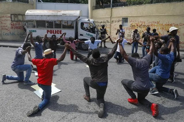 People kneel outside the Justice Ministry to demand the resignation of Minister Liszt Quitel to protest kidnappings in Port-au-Prince, Haiti, Tuesday, October 26, 2021. Worker unions along with residents called for a general strike to demand the end of kidnappings, violence and insecurity in the streets. (Photo by Joseph Odelyn/AP Photo)