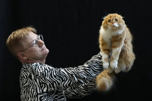 A Scottish Fold cat is held up by a judge at the Cat Extravaganza event at Olympia in London, Sunday, February 18, 2024. Loving Cats Worldwide brought its Cat Extravaganza and Rescue Awareness Event to London, where visitors could learn all about this intelligent species by observing the show's five judging rings. Plus, meet with local rescues and charities, as well as hear educational anecdotes about different cat breeds. (Photo by Kirsty Wigglesworth/AP Photo)