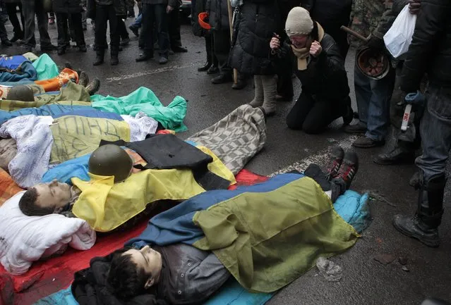 Activists pay respects to protesters killed in clashes with police, in Kiev's Independence Square, the epicenter of the country's current unrest, Thursday, February 20, 2014. (Photo by Sergei Chuzavkov/AP Photo)