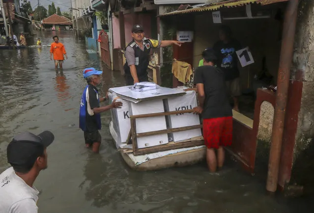 In this Tuesday, April 16, 2019, file photo, workers transport ballot boxes and other election paraphernalia through a flooded neighborhood due to heavy rain in Banding, West Java. The Indonesian presidential election is the world’s biggest direct vote for a national leader. (Photo by AP Photo/Stringer)