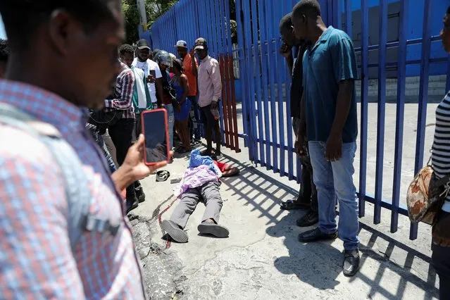 People look at the body of a dead man in Port-au-Prince, Haiti, on April 1, 2024. (Photo by Ralph Tedy Erol/Reuters)