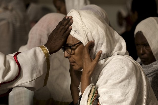 A Christian Orthodox woman is blessed by a priest during morning mass at Medhane Alem Cathedral in Addis Ababa, Ethiopia, May 18, 2015. (Photo by Siegfried Modola/Reuters)