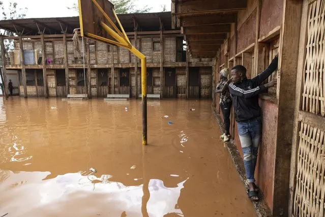 Residents of Mathare slum use the wall to cross a flooded school field, following heavy down pour in the capital, Nairobi on April 24, 2024. Storms and flash floods wreaked devastation across the Kenyan capital Nairobi on April 24, 2024, claiming at least four lives. (Photo by Simon Maina/AFP Photo)