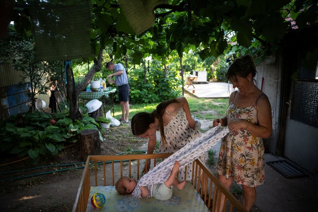 Petra Pogany-Bago, 24, and her mother Marsa Irma play with Petra's son, Mihaly Pogany, at their farm near Kecskemet, Hungary, July 16, 2023. Laszlo Kemencei, 28, who also lives sustainably, estimates there are around 1,000 families trying to embrace some form of sustainability, either alone or as part of informal barter arrangements, or as part of more structured eco-villages. “We should reduce our wants just a little, as now we live in a world where we sit on a galloping horse and when the horse dies, we just jump on another one”, he says. “This is scary, but I think everyone should do their best within their limits”. (Photo by Marton Monus/Reuters)