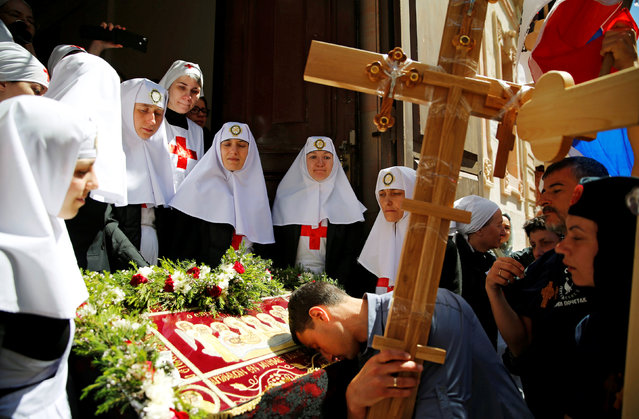 A Serbian Orthodox Christian worshipper holds a cross as he kisses a Tapestry during a procession along Via Dolorosa on holy week's Good Friday in Jerusalem's Old City April 29, 2016. (Photo by Ammar Awad/Reuters)