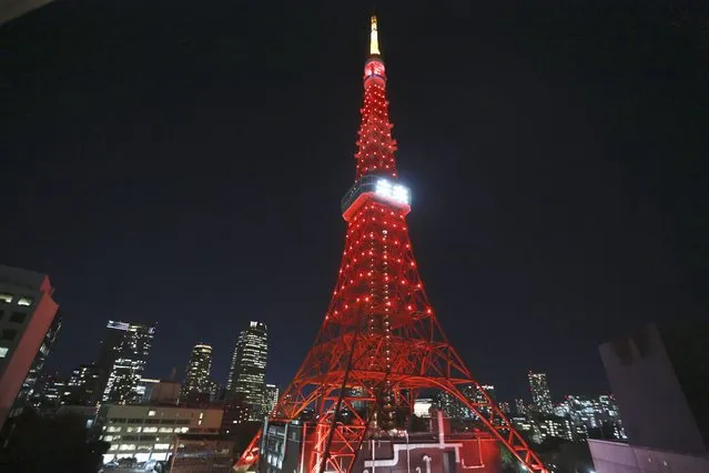 The Tokyo Tower is illuminated in red and with a display in Japanese, center, to cerebrate the diplomatic relationship between Japan and China and the Beijing Olympics, in Tokyo, Monday, January 31, 2022. The two projected Japanese characters read, “Future”. (Photo by Koji Sasahara/AP Photo)