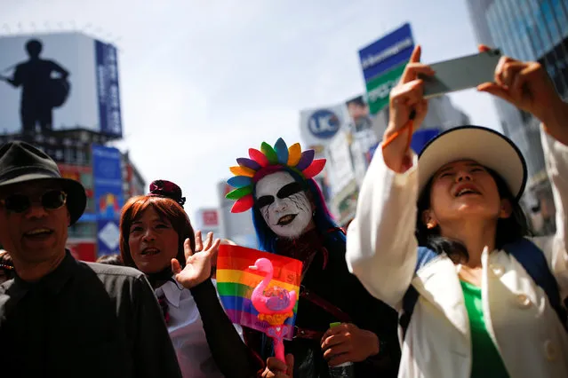 A woman takes pictures of revellers as they take part in the Tokyo Rainbow Pride parade celebrating lesbian, gay, bisexual, and transgender (LGBT) culture in Tokyo, Japan, May 8, 2016. (Photo by Thomas Peter/Reuters)