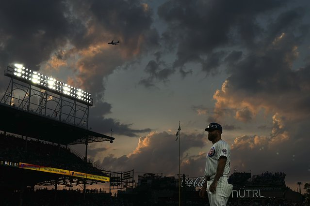 Chicago Cubs first base coach Mike Napoli looks into the stands as a commercial airplane make its way to O'Hare International Airport during the fourth inning of a baseball game against the San Francisco Giants, Monday, June 17, 2024, in Chicago. (Photo by Charles Rex Arbogas/AP Photot)