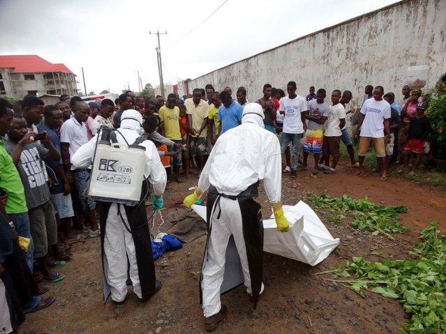 Healthcare workers prepare to remove the body of a man suspected of carrying Ebola in Monrovia, Liberia, July 17, 2015. (Photo by James Giahyue/Reuters)