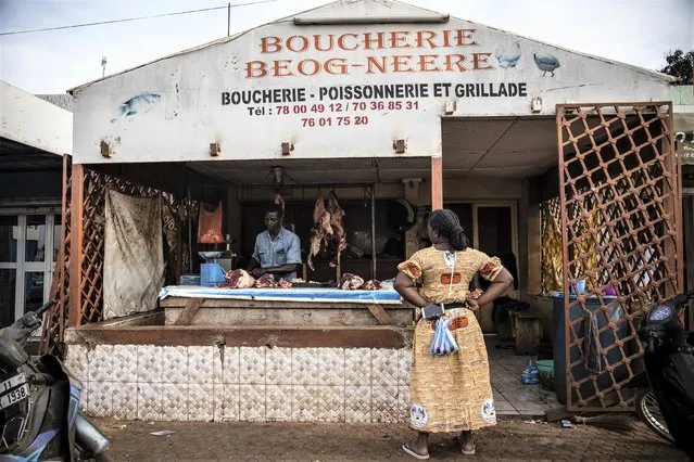 A woman waits for her order at a Butcher shop in the Gounghin district of Ouagadougou Wednesday January 26, 2022. (Photo by Sophie Garcia/AP Photo)