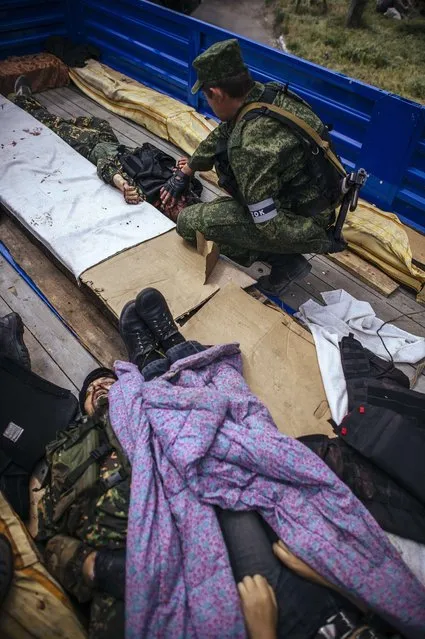 A pro-Russian gunman touches the body of his friend in a truck at a checkpoint outside of the eastern Ukrainian city of Donetsk on May 23, 2014. At least five people were killed in fighting early Friday between pro-Russian militiamen and Ukrainian forces near the eastern city of Donetsk, an AFP photographer said. Fighting in the east has witnessed a bloody resurgence ahead of Sunday's presidential election that the pro-Russian insurgents have vowed to disrupt. (Photo by Dimitar Dilkoff/AFP Photo)