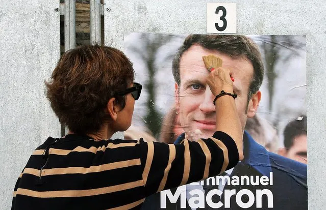 A supporter of French President and centrist candidate for reelection Emmanuel Macron glues a campaign poster in Saint Jean de Luz, southwestern France, Tuesday, April 12, 2022. President Emmanuel Macron may be ahead in the presidential race so far, but he warned his supporters that “nothing is done” and his runoff battle with far-right challenger Marine Le Pen will be a hard fight. (Photo by Bob Edme/AP Photo)