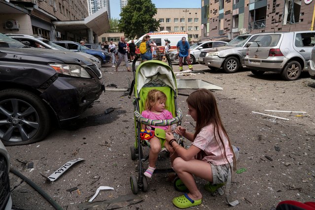 Children wait near the site of Okhmatdyt children’s hospital hit by Russian missiles, in Kyiv, Ukraine, Monday, July 8, 2024. Russian missiles have killed several people and struck a children’s hospital in the Ukrainian capital, Kyiv, authorities say. (Photo by Evgeniy Maloletka/AP Photo)