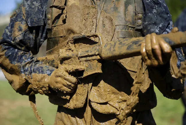 A first-year midshipman, known as a “plebe”, carries a dummy rifle covered in mud during Sea Trials, a day-long training exercise that caps off their plebe year at the U.S. Naval Academy in Annapolis, Md., Tuesday, May 16, 2017. (Photo by Patrick Semansky/AP Photo)