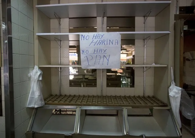 In this March 20, 2017 photo, a sign that reads in Spanish “No flour. No bread” hangs from an empty shelf at a privately owned bakery in Caracas, Venezuela. The most recent survey on living standards by three major universities found that 93 percent of Venezuelans at the end of last year said they didn't have enough money to buy food, scraping by instead by skipping meals and reducing calories. (Photo by Fernando Llano/AP Photo)